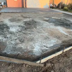 Plac budowy podjazdu z kamienia. Widać szalunki i przygotowany teren pod wylanie betonu.