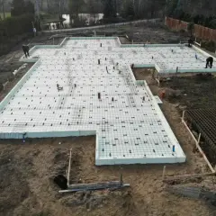Fundament pod budowę z siatką zbrojeniową i rurami. Szybki beton zostanie wkrótce wylany na tę przygotowaną powierzchnię.