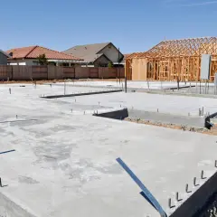Fundamenty domów w budowie, widać chudy beton i szkielety drewniane.