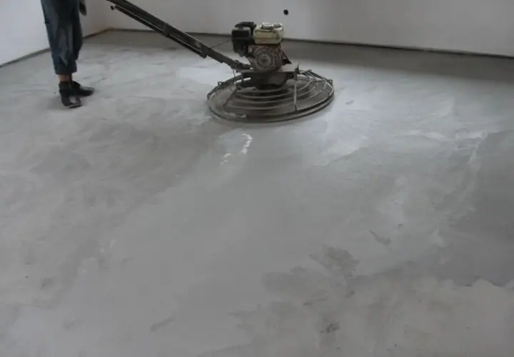 Pracownik poleruje betonową posadzkę maszyną. Powierzchnia jest gładka i jednolita, tworząc nowoczesny **beton polerowany**.