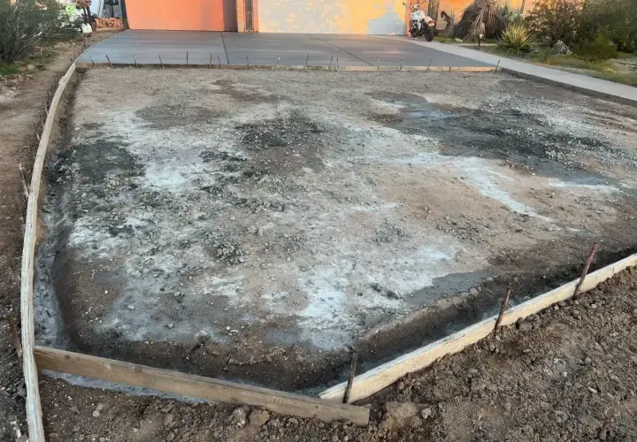 Plac budowy podjazdu z kamienia. Widać szalunki i przygotowany teren pod wylanie betonu.