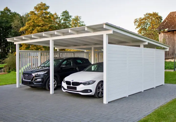 Nowoczesna budowa wiaty chroni dwa samochody: czarnego SUV-a i białe BMW. Elegancka konstrukcja z białymi panelami i dachem.