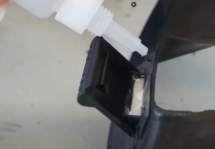 Kropla cyjanoakrylu z butelki precyzyjnie aplikowana na czarny plastikowy element, naprawiając go.