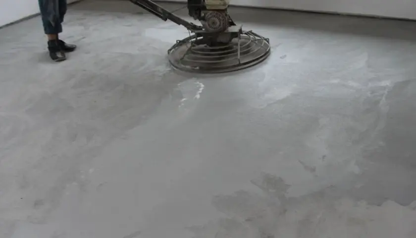 Pracownik poleruje betonową posadzkę maszyną. Powierzchnia jest gładka i jednolita, tworząc nowoczesny **beton polerowany**.