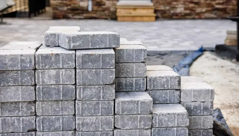 Stosy szarych kostek brukowych, gotowych do ułożenia. Różne rodzaje kostki brukowej czekają na stworzenie pięknego podjazdu.