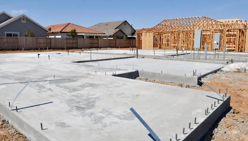 Fundamenty domów w budowie, widać chudy beton i szkielety drewniane.