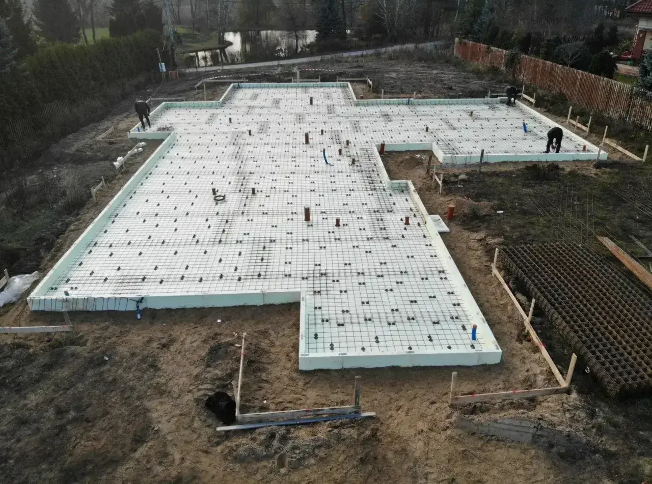 Fundament pod budowę z siatką zbrojeniową i rurami. Szybki beton zostanie wkrótce wylany na tę przygotowaną powierzchnię.